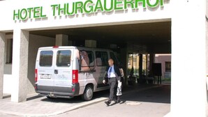 A van parked in front of Hotel Thurgauerhof with a man walking by.