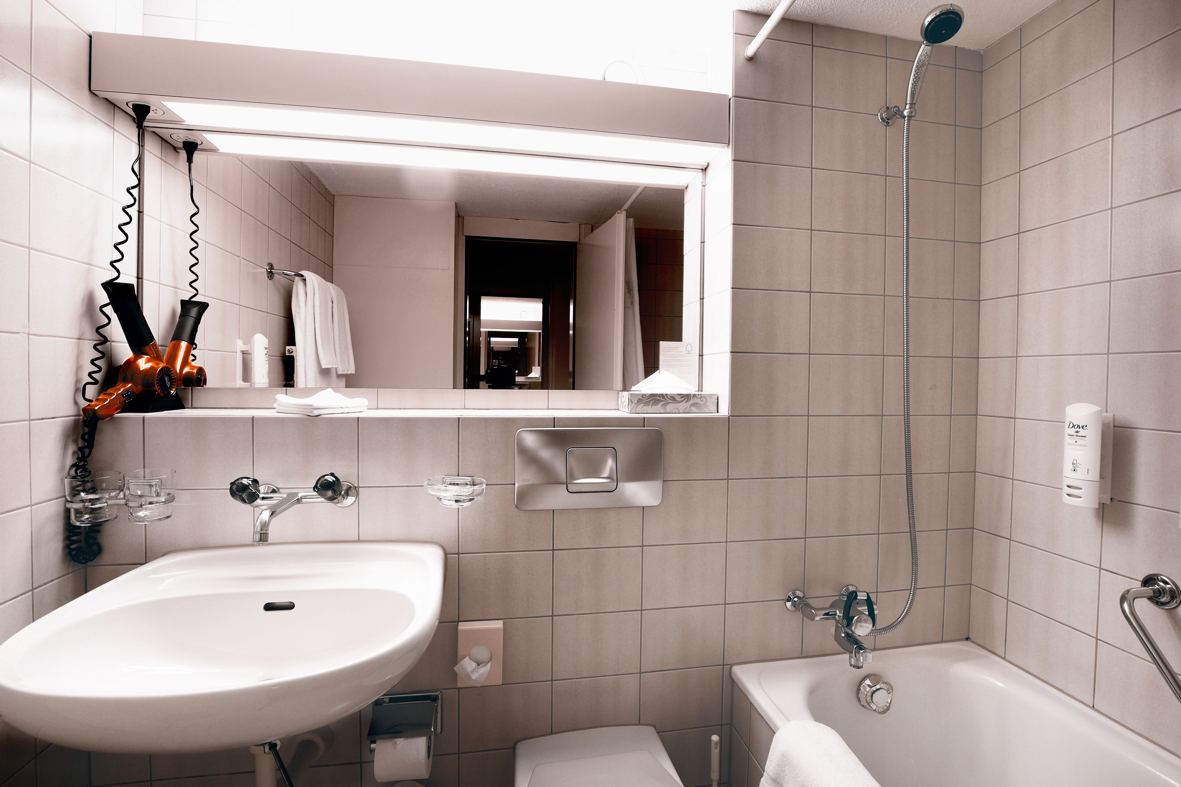 Een moderne badkamer met een wastafel, spiegel, douche en toilet.