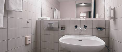 Un baño moderno con lavamanos, inodoro y toallero blancos.