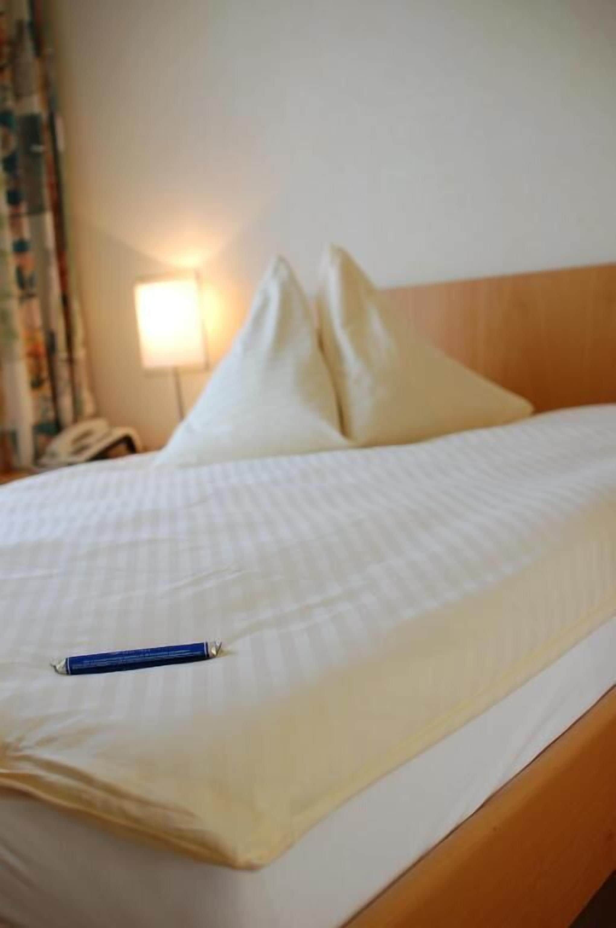 Un letto rifatto con un cuscino e una penna sul copripiumino.