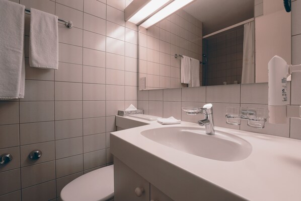 A modern bathroom with a white sink, mirror, and toilet.