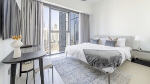 Ein modernes Hotelzimmer mit einem großen Bett, einem Schreibtisch und Blick auf die Stadt.