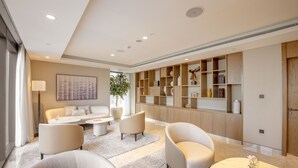 Ein modernes Wohnzimmer mit einer Couch, Sesseln, einem Couchtisch und einem Bücherregal.