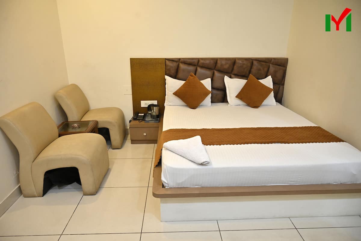 A hotel room with a large bed, a nightstand, a chair, and a small table.