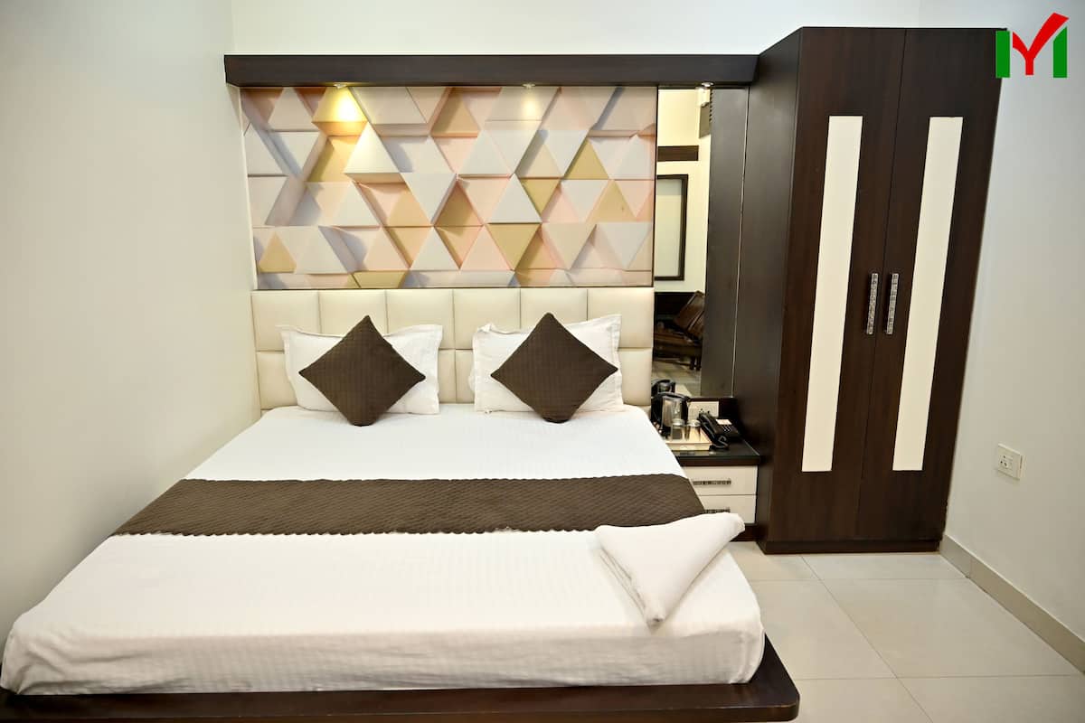 A neatly made bed with a headboard, a wardrobe with a mirror, and a geometric-patterned wall.