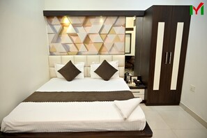 A neatly made bed with a headboard, a wardrobe with a mirror, and a geometric-patterned wall.