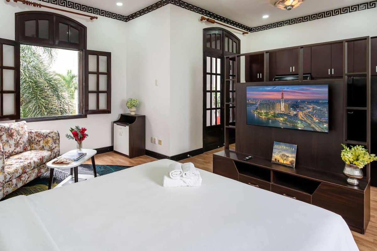 Une chambre d’hôtel avec un lit, un canapé, une télévision et une armoire.