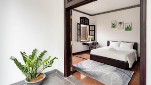 A hotel room with a bed, a desk, a chair, a potted plant, and a mirror. - 5H Garden  (Ho Chi Minh City)