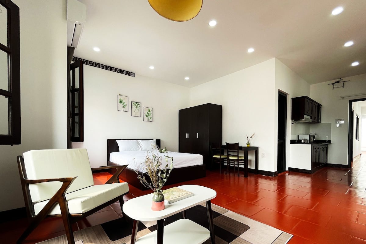 Une chambre d’hôtel moderne comprenant un lit, un coin salon avec une table et une kitchenette.