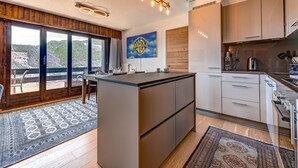 Una cocina moderna con una isla central, armarios de madera y un amplio ventanal con vistas a un paisaje pintoresco.