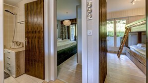 Un dormitorio con cama, puerta de madera, baño con ducha y vistas al exterior.