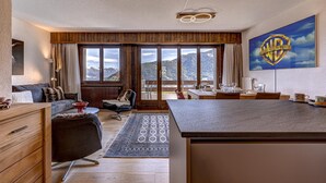 Una sala moderna con techo de madera, un ventanal y vistas a montañas.