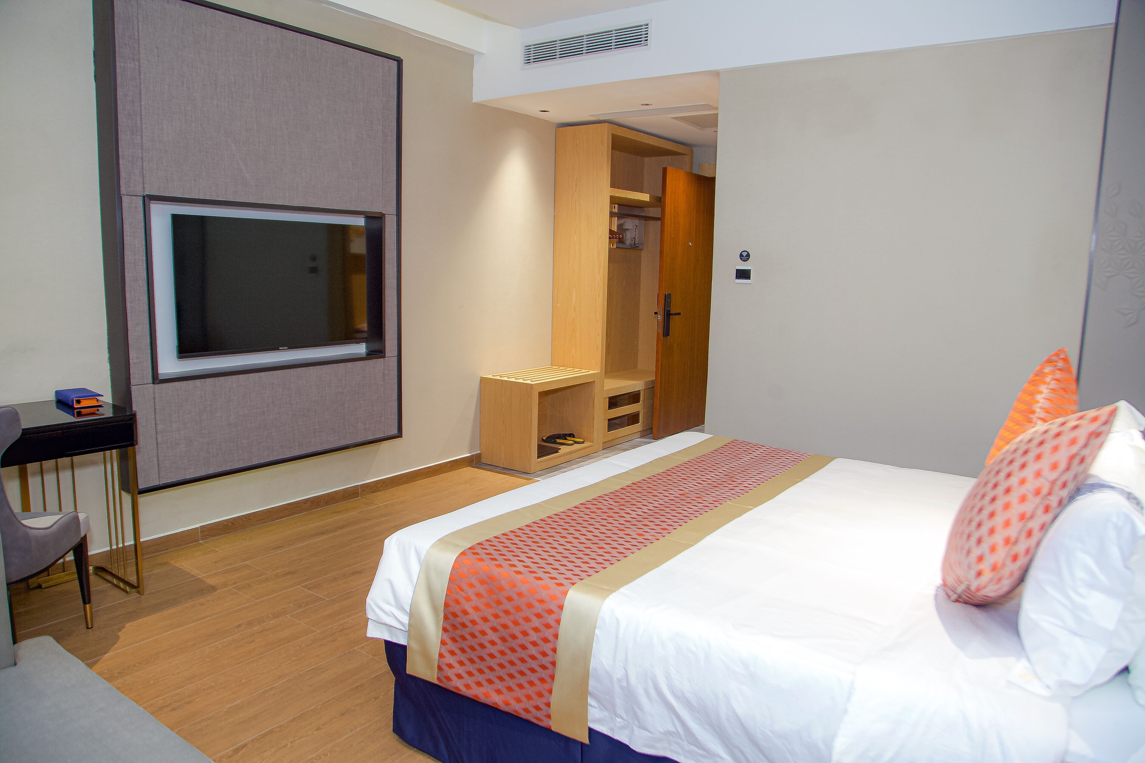 A hotel room with a bed, a desk, a television, and a wardrobe.