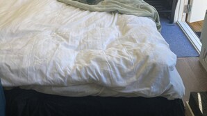 Ein Bett mit weißer Bettwäsche, einer grauen Tasse und einer grünen Decke.