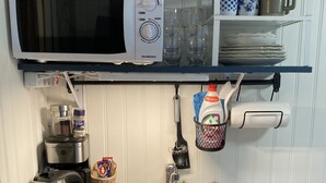 Eine Küche mit Mikrowelle, Kaffeemaschine, Wasserkocher und Spüle mit Geschirrgestell.