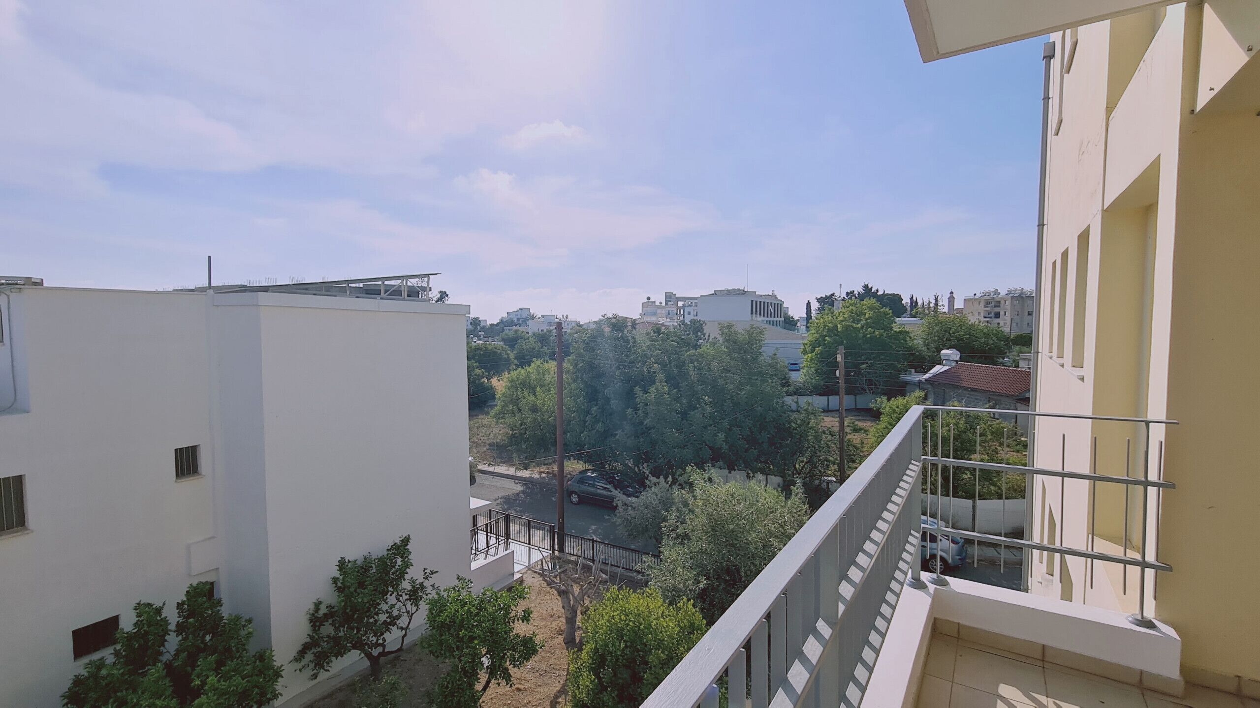 Un immeuble d’habitation doté d’un balcon donnant sur une rue et des arbres.