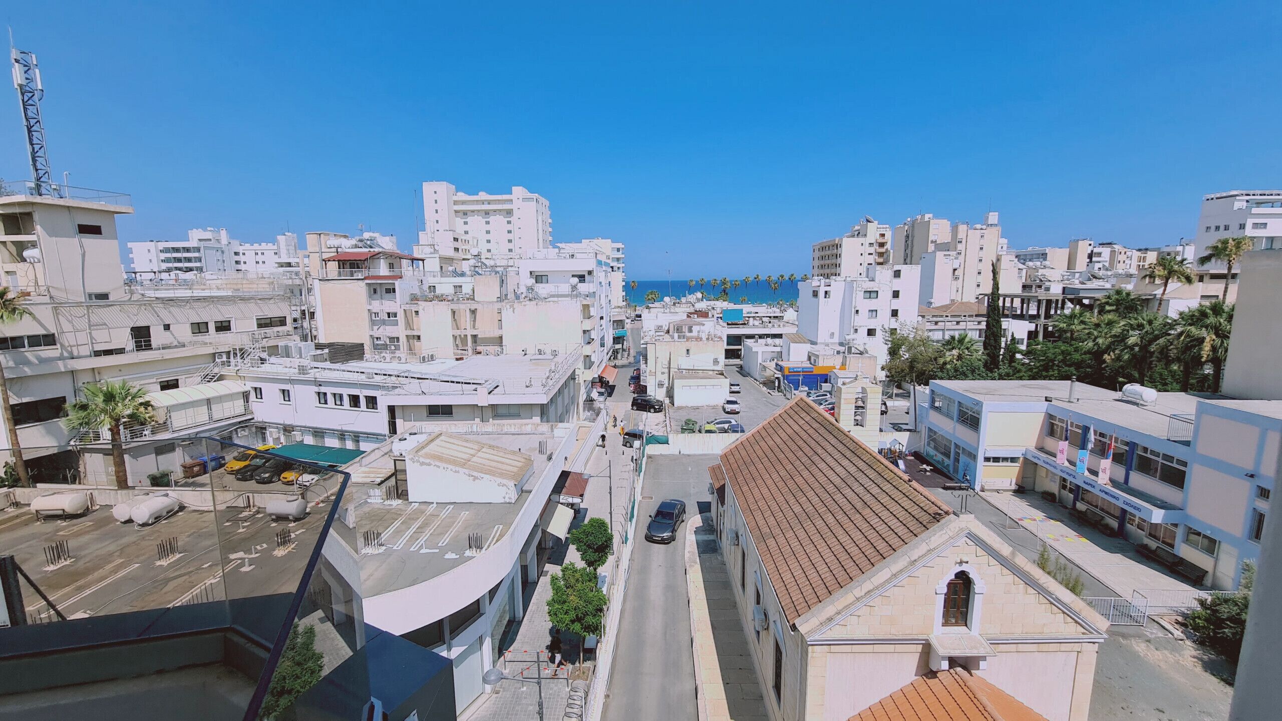 Paisagem costeira urbana com edifícios modernos, céu claro e vista para o mar.