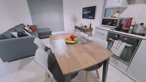 Een moderne keuken met een eettafel, stoelen, een magnetron, een waterkoker en een televisie waarop Netflix wordt getoond.