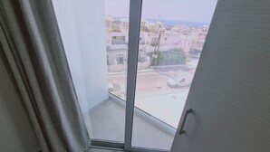 A view from a balcony with a clear sky, a street, and buildings in the background.