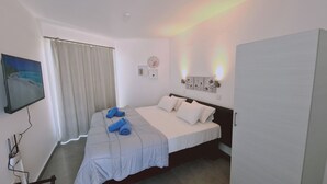 Un dormitorio con cama, televisión, reloj y lámpara de pared.