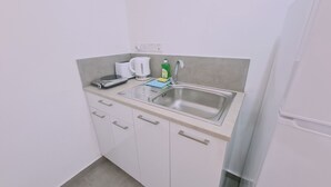 A small kitchenette with a sink, a kettle, a scale, and a bottle of dish soap.