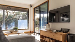 Ein modernes Wohnzimmer mit großem Fenster, Flachbildfernseher und Holzkonsole.