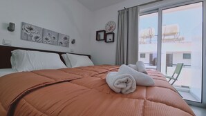 Hotellihuone, jossa on suuri sänky, ikkunasta avautuva näkymä kaupunkiin ja seinällä oleva kello.