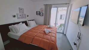 Une chambre d’hôtel avec un lit, une télévision et un balcon équipé de chaises.