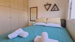 A bedroom with a bed, two pillows, a bedside table, a lamp, and a wardrobe. - STAY Naturaleza Penthouse (Limassol)