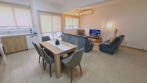 Eine moderne Wohnung mit Essbereich, Küche, Wohnzimmer und Fernseher.