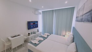 A hotel room with a bed, a desk, a chair, a TV, and a window with curtains. - STAY Napa Oasis Studio (Ayia Napa)