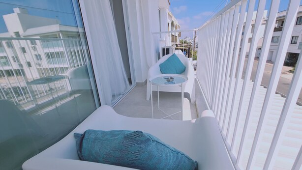 A balcony with a white sofa, a small table, and a patterned cushion. - STAY Napa Oasis Studio (Ayia Napa)