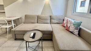 A modern living room with a sofa, a small table, and a remote control on the table. - STAY Napa Aura Apartment (Ayia Napa)