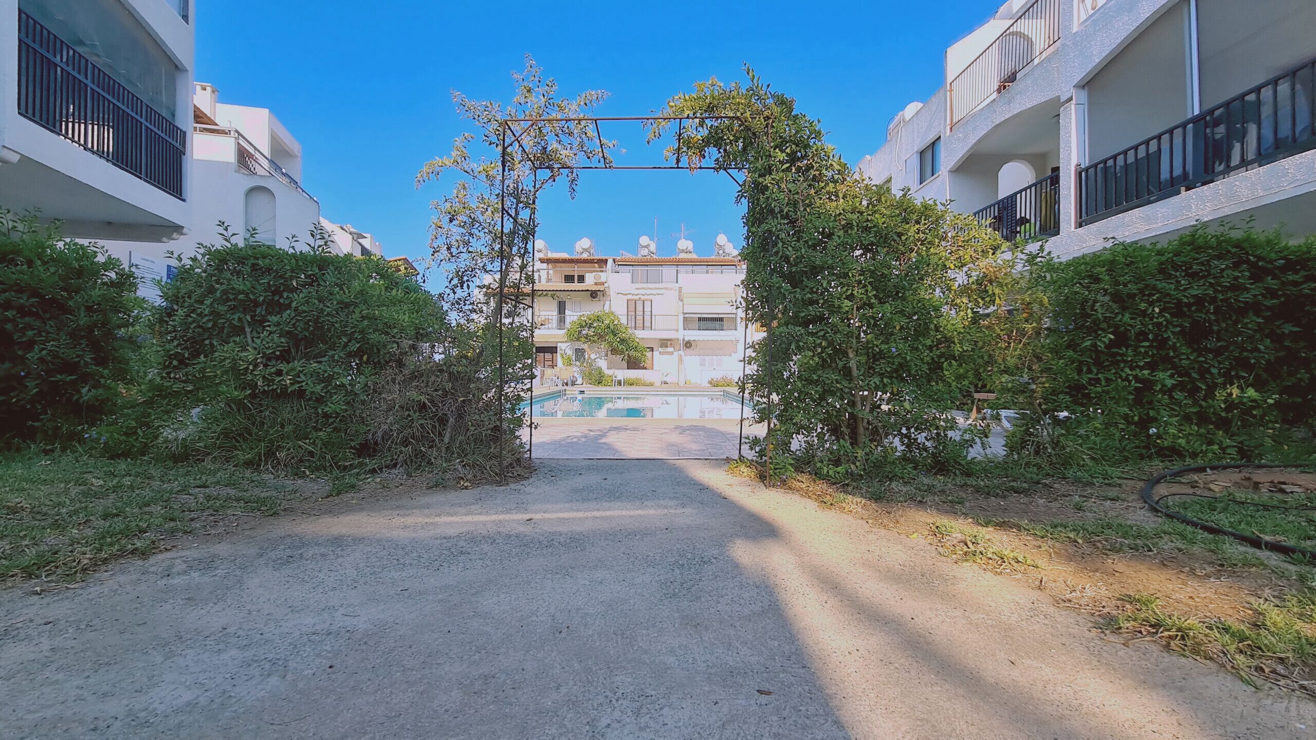 A gated entrance to a residential area with a swimming pool visible through the gate.