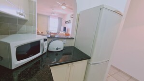 Eine kompakte Küche mit einer weißen Mikrowelle, einem Toaster und einem Kühlschrank.