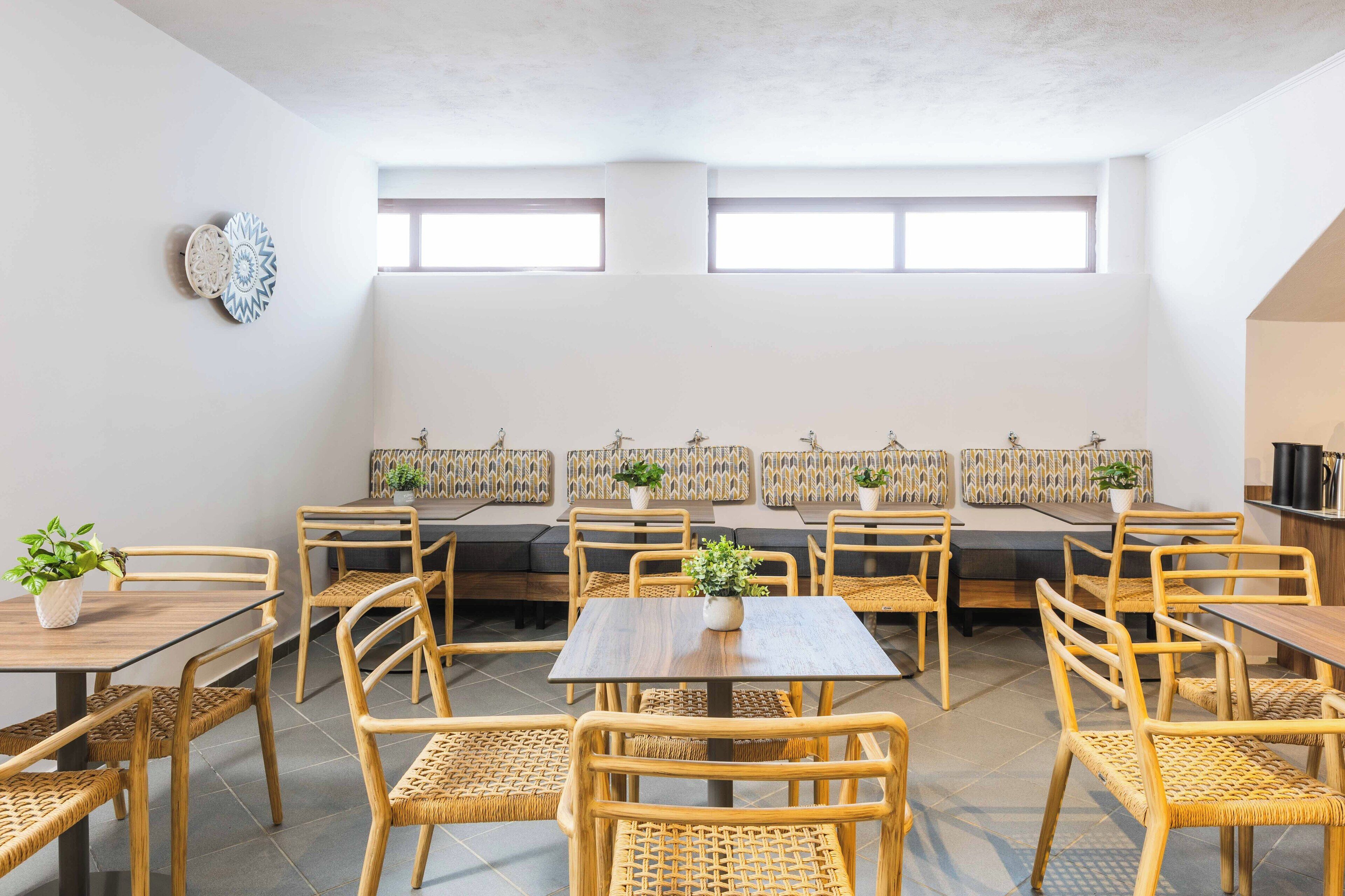 A spacious indoor seating area with multiple tables and chairs, a long bench, and decorative wall panels.