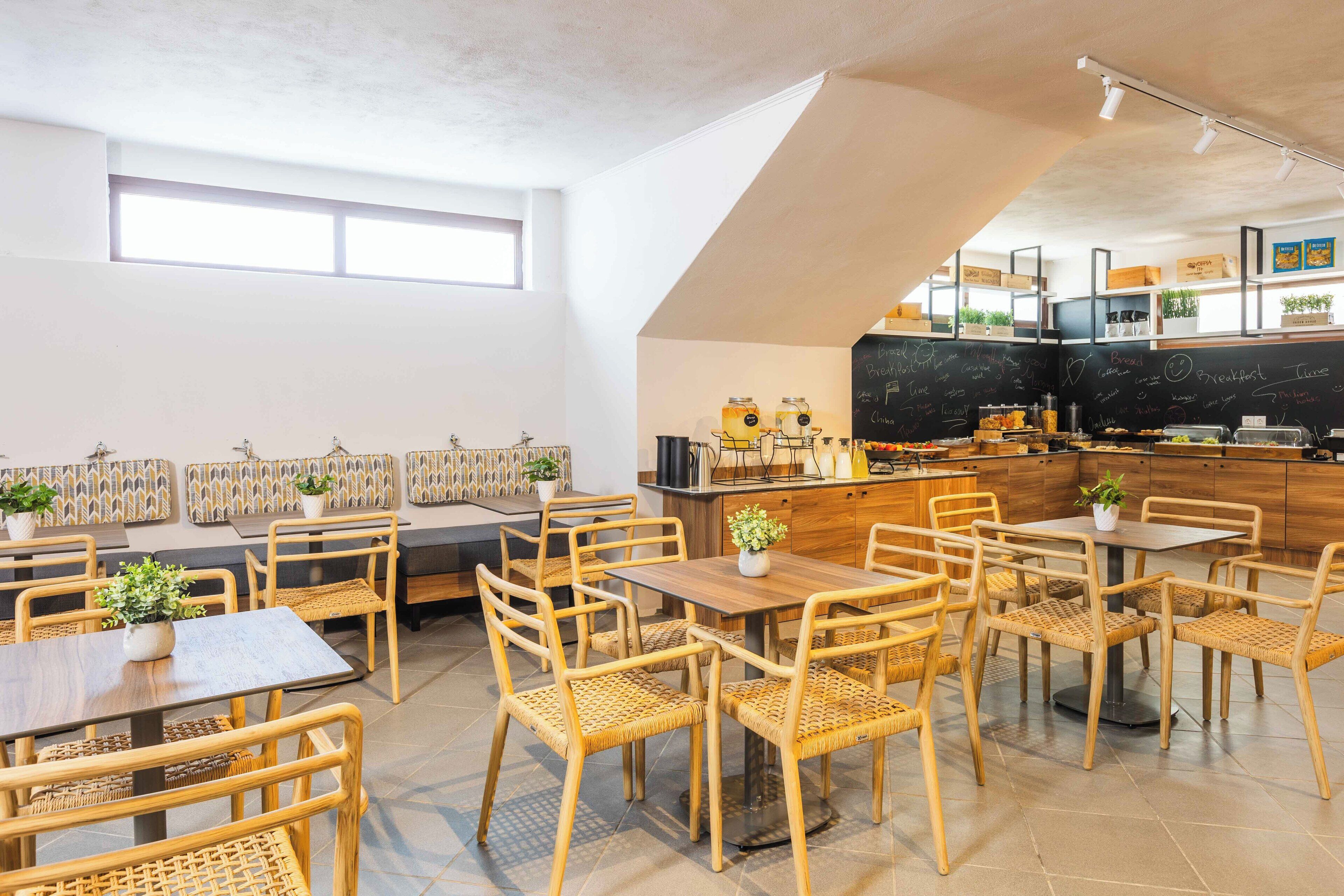 A restaurant with wooden furniture, a chalkboard menu, and a kitchen area.