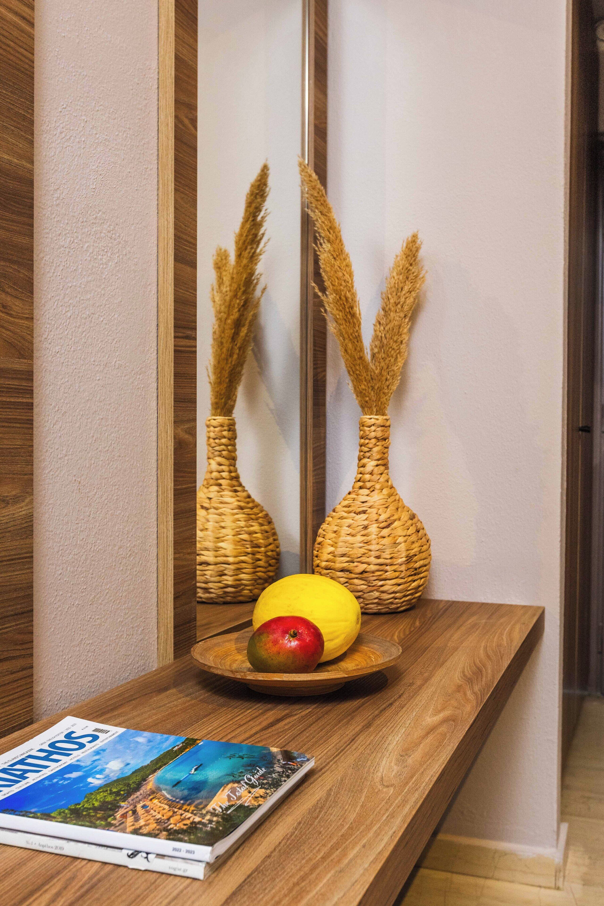 A wooden table with two woven vases, a plate with an apple and a lemon, and a magazine.