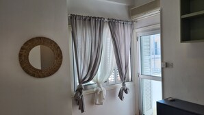 A room with a window, a mirror, and a wall-mounted air conditioning unit. - STAY Antique Apartment (Larnaca)