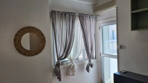 Una habitación con ventana, espejo y aire acondicionado instalado en la pared.