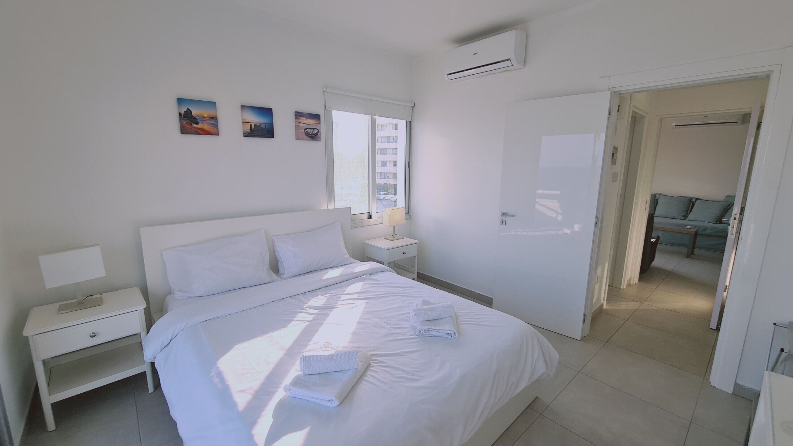 Un dormitorio limpio y moderno con una cama grande, mesitas de noche y vistas al exterior por una ventana.