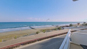 A beach view with a road, a lifeguard tower, and a clear sky. - STAY Beach Wave Apartment (Larnaca)