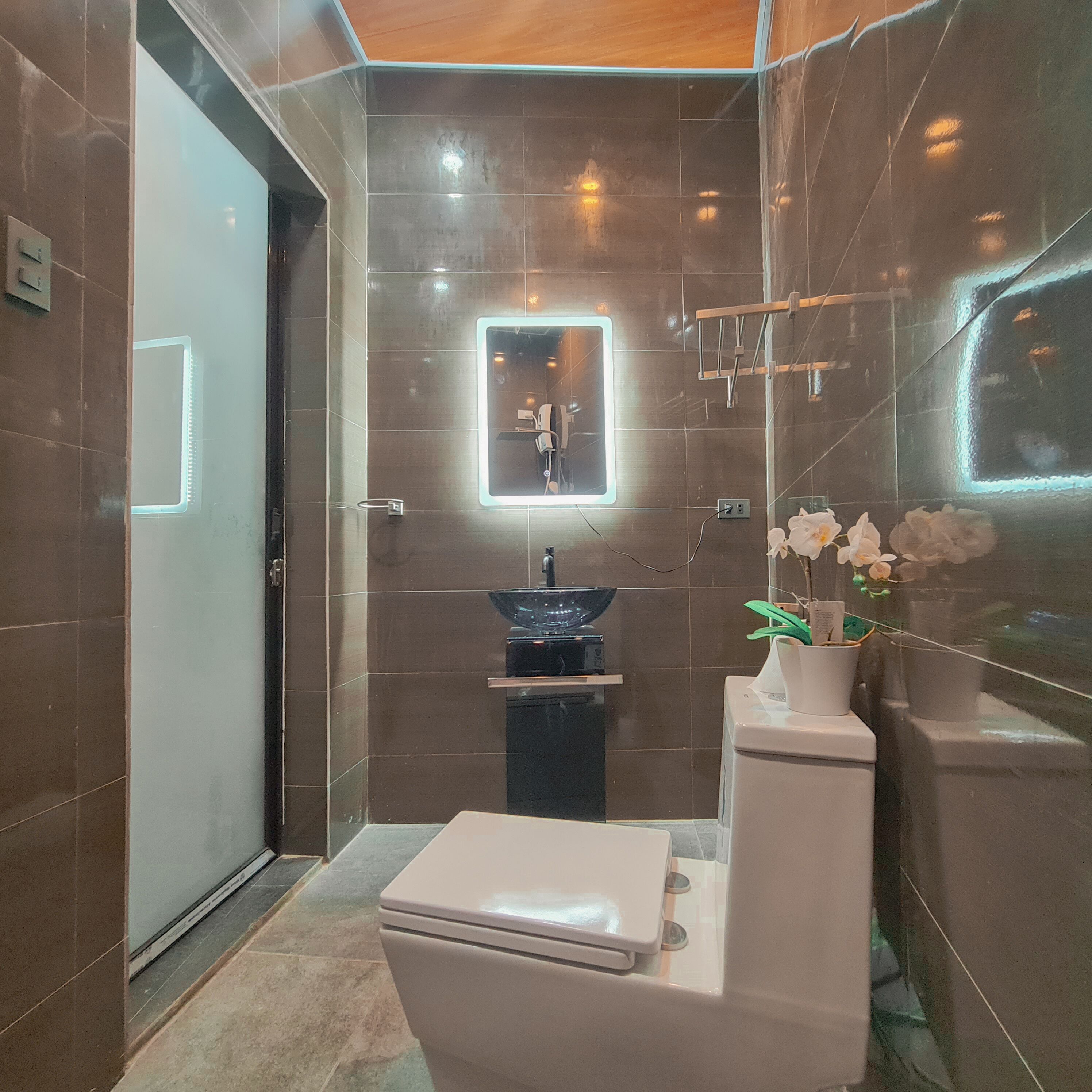 Une salle de bain moderne équipée de toilettes, d’un lavabo et d’un miroir avec éclairage.
