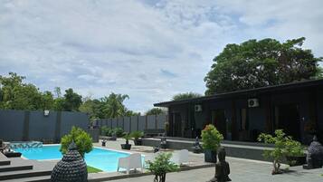 A modern outdoor area with a swimming pool, seating areas, and a building with air conditioning units.