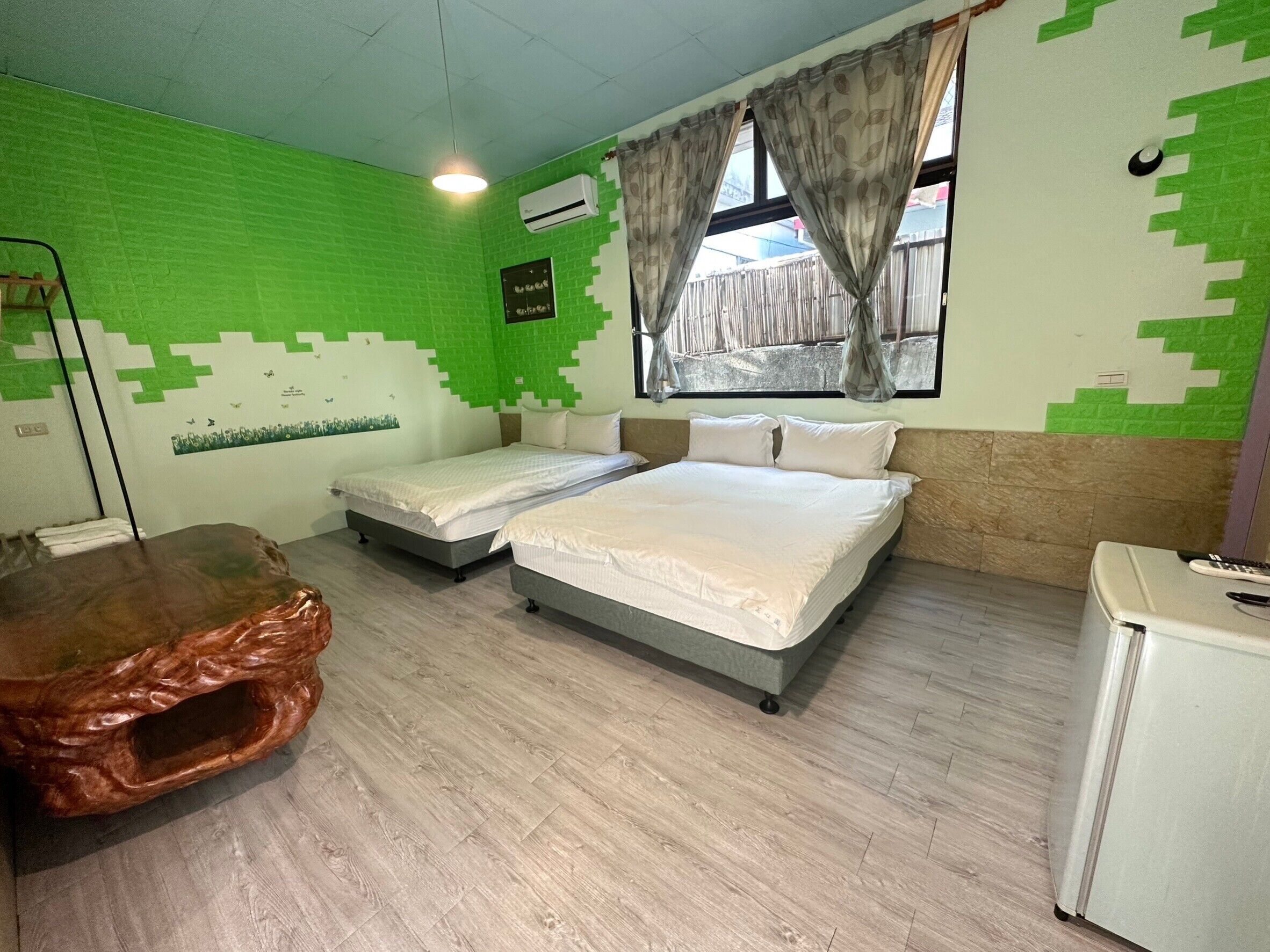 A room with two beds, a wooden table, and a small white cabinet.