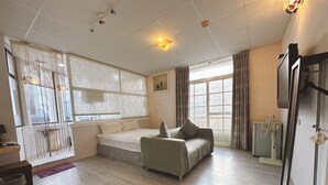 A spacious living room with a sofa, a bed, and a large window. - Zhi Xin Yuan (Hualien City)