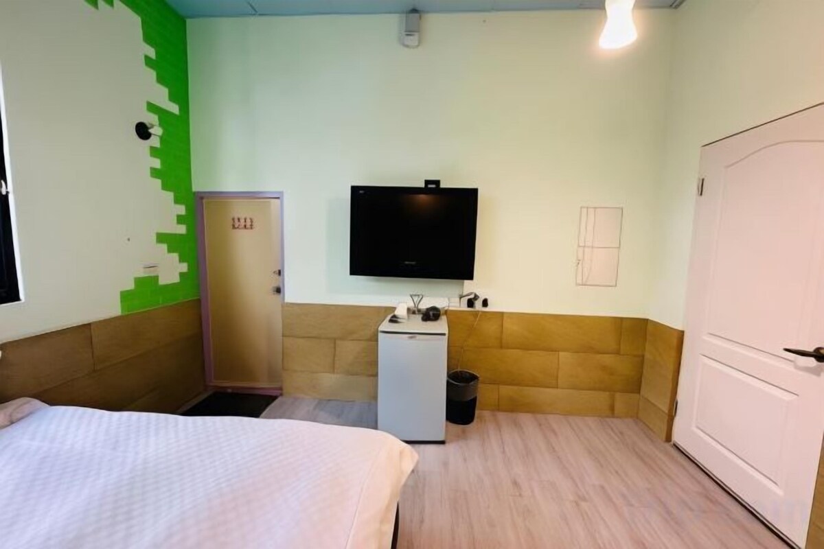 Habitación de hotel con cama, kitchenette pequeña, televisor y armario.