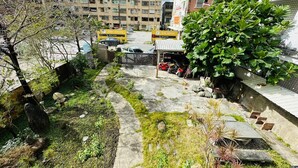 A courtyard with a pathway, greenery, and parked cars. - Zhi Xin Yuan (Hualien City)