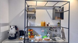 Eine Küchenzeile mit Kaffeemaschine, Obst, Gewürzen und Regalen.