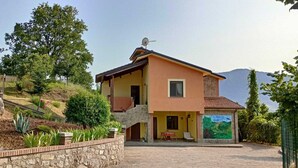 Ein zweistöckiges Haus mit einer Steinmauer, einem kleinen Balkon und einem Garten mit verschiedenen Pflanzen.